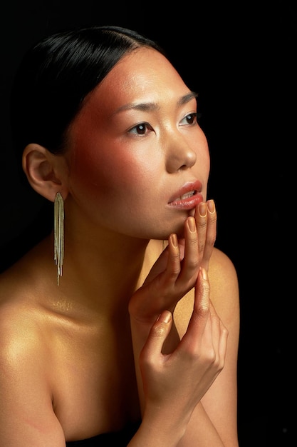 Foto een aziatisch meisje op een zwarte achtergrond in de studio goud dunne sleutelbeenderen het rijk van schoonheid en parfum emotie broeierige reflectie