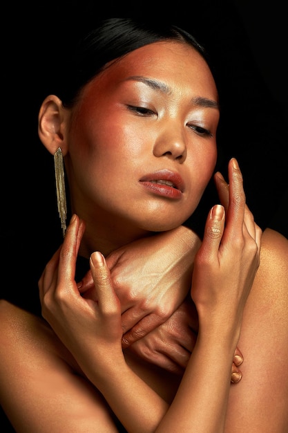 Foto een aziatisch meisje op een zwarte achtergrond in de studio goud dunne sleutelbeenderen het rijk van schoonheid en parfum handen omhelzen de nek zorg
