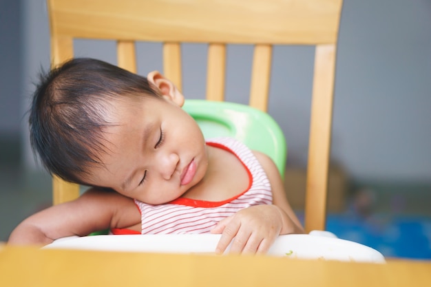 Een Aziatische baby van een jaar en drie maanden slaapt tijdens het eten