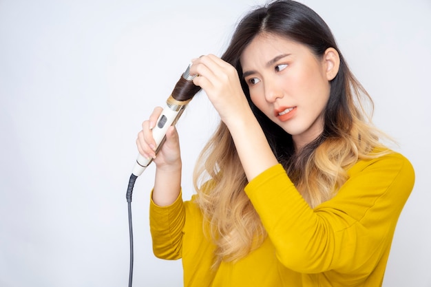 Een aziatische blogger, beautyblogger, maakt een video van zichzelf terwijl ze een oranje lippenstift draagt in een studio.