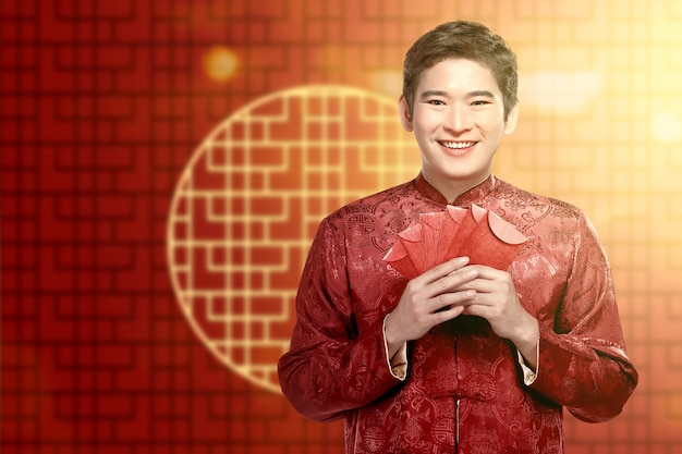 Een Aziatische Chinese man in een cheongsam-jurk met rode enveloppen