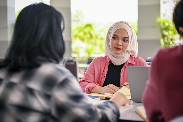 Een Aziatische islamitische studente is in gesprek met haar vrienden