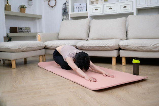 Een Aziatische jonge vrouw is aan het trainen op een fitnessmat om thuis een gezond levensstijlconcept uit te oefenen