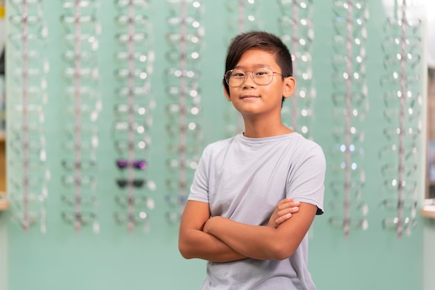 Een aziatische jongen die een bril probeert in een opticienwinkel Achtergrond met een glazen vitrine