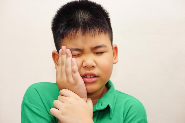 Een Aziatische jongen gebruikt je handen om je wangen vast te houden vanwege de pijn van kiespijn