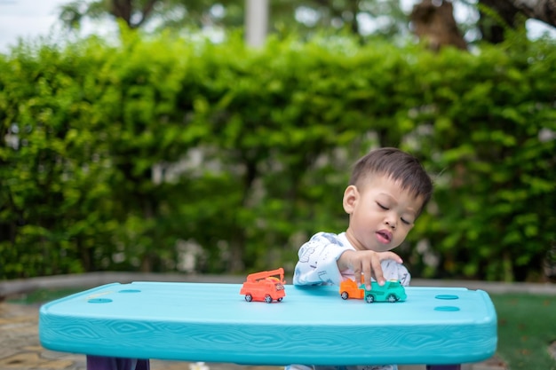 Een Aziatische jongen van één jaar speelt in een speelgoedwagen in zijn tuin.