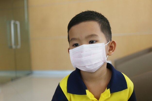 Een Aziatische jongen van ongeveer vijf jaar die een masker draagt om ademhalingsziekten te voorkomen