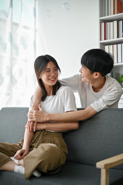 Een Aziatische man die zijn vriendin van achteren omhelst terwijl hij samen ontspant in de woonkamer