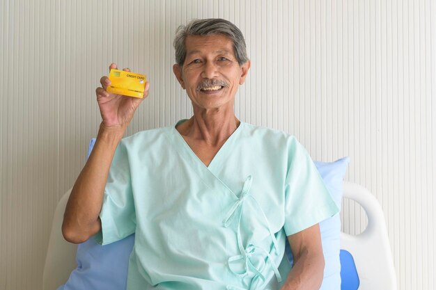 Een Aziatische Senior geduldige man toont creditcard in het ziekenhuis