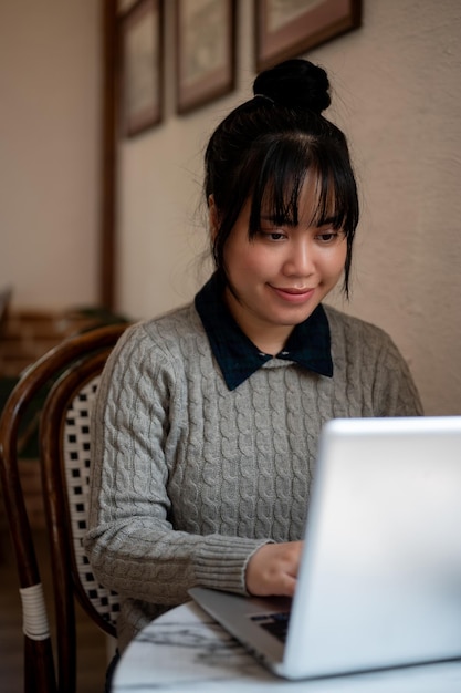 Een Aziatische vrouw concentreert zich op haar werk op haar laptop en werkt op afstand in een café