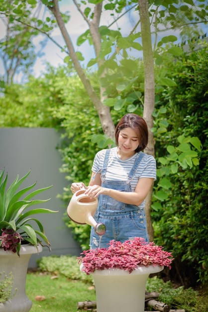 Een Aziatische vrouw geeft planten water in de tuin