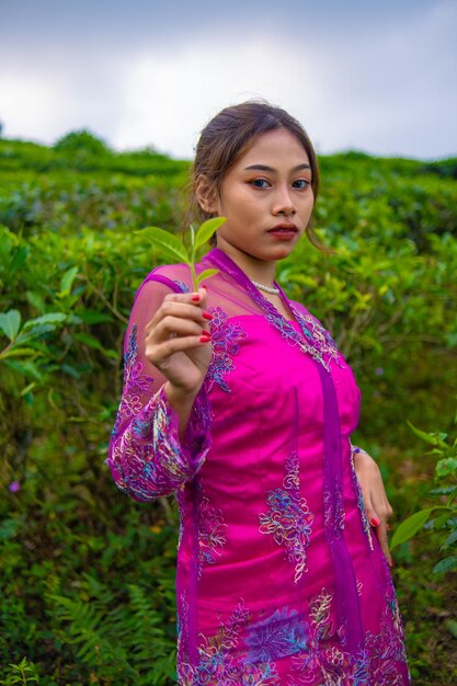 Foto een aziatische vrouw in een roze jurk staat 's morgens voor een theetuin