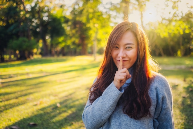 Een Aziatische vrouw met wijsvinger op de lippen, die vraagt om stil te zijn of geheim te houden