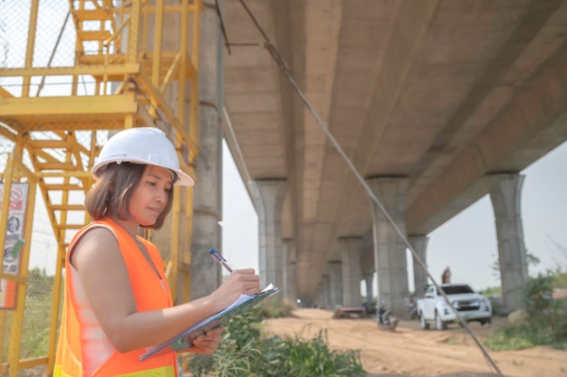 Een Aziatische vrouwelijke ingenieur werkt op de bouwplaats van een snelwegbrug