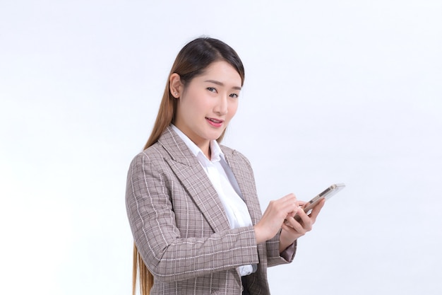 Een Aziatische werkende vrouw in een formeel pak in een wit overhemd belt om informatie te controleren.
