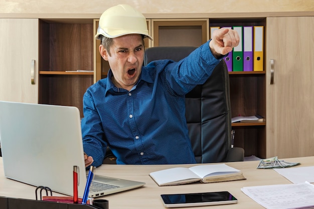 Een baas in een helm aan zijn bureau schreeuwt naar zijn ondergeschikten en gebaart naar de uitgang. Bouwer, ingenieur, proctor, voorman.