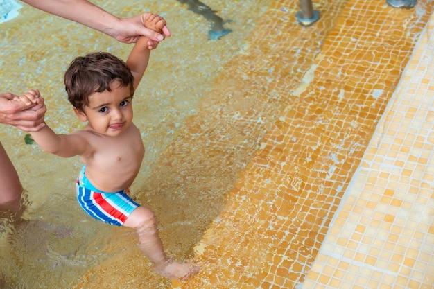 Een baby die uit het zwembad komt met de hulp van zijn moeders armen