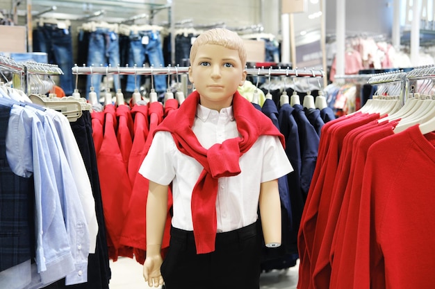 Een baby-etalagepop in een hemd, zwarte broek en rode trui in een winkelcentrum Casual kinderkledingwinkel Moderne mode voor kinderen Horizontale foto