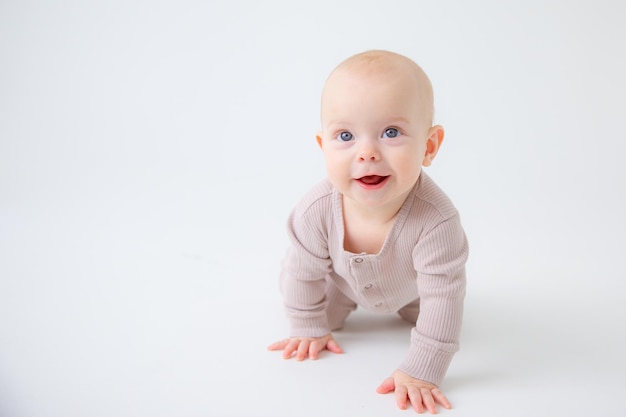 Een baby in een bodysuit kruipt op een witte achtergrond studio-opnamen