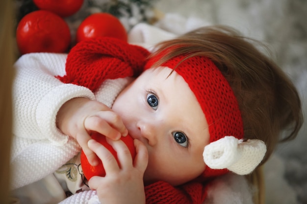Een baby in een rode muts met ballen in het interieur van het nieuwe jaar.