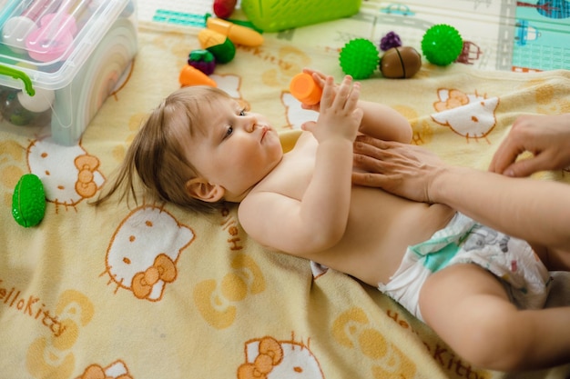 Een baby ligt op een bed met een dekentje waarop 'baby' erop staat