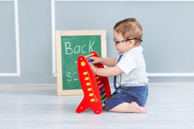 Een baby met een bril en een schoolbord waarop staat binnenkort naar school zit met rekeningen