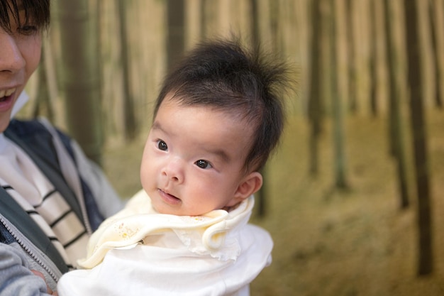 Een baby met een gele sjaal wordt gedragen door een vrouw.