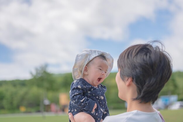 Een baby met een hoed op geeuwt in een park.