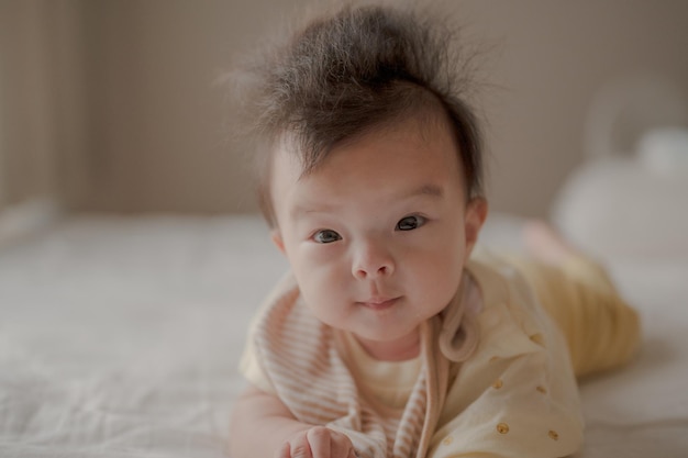 Een baby met een rommelig kapsel ligt op een bed.