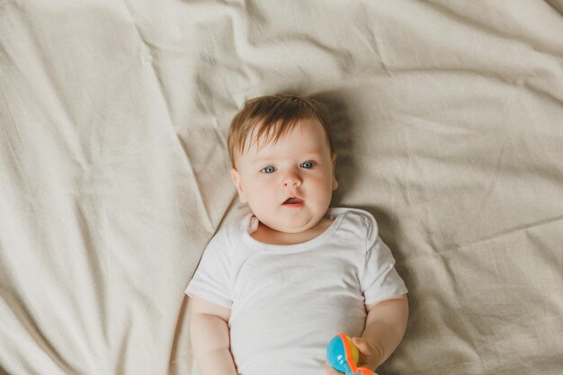 Een baby met een tander en een rammel op een katoenen bed Tandenvorming Kinderenartikel kopieerruimte