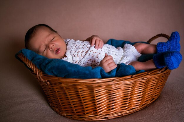 Een baby slaapt in een mand met een blauwe deken.