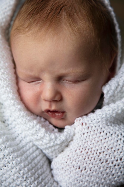 Een baby van een maand oud in slaap gewikkeld in een witte deken