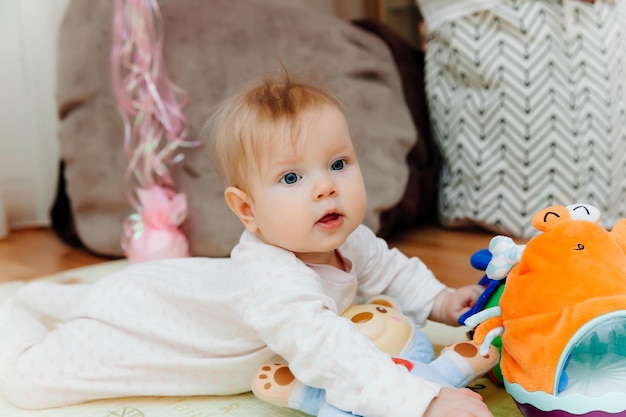 Een baby van zes maanden speelt op de grond met kleurrijk speelgoed De baby leert kruipen portret van een baby van 6 maanden oud