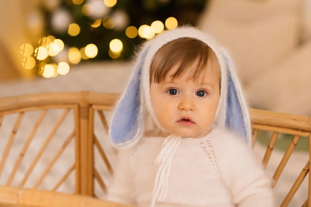 Een baby zit op een bank voor een kerstboom