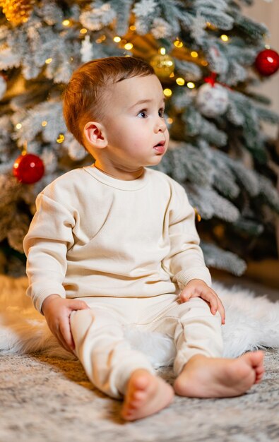 Een baby zit voor een kerstboom