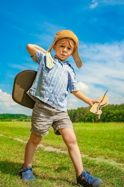 Een babyjongen bij het vliegtuig speelt op de natuur in het park. Jongen op vakantiepiloot.