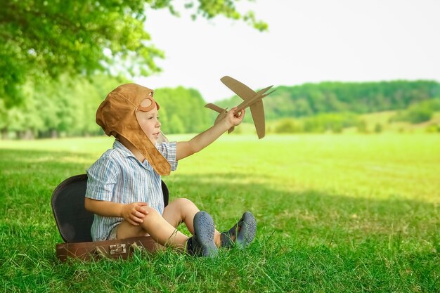 Een babyjongen bij het vliegtuig speelt op de natuur in het park. Jongen op vakantiepiloot.