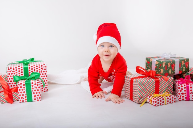 Een babymeisje in een kerstmankostuum met geschenken op een witte achtergrond Santa Claus Helper