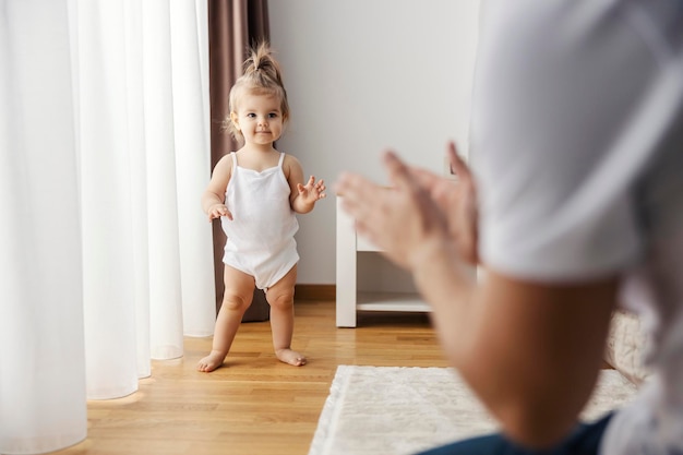 Een babymeisje staat alleen en leert lopen