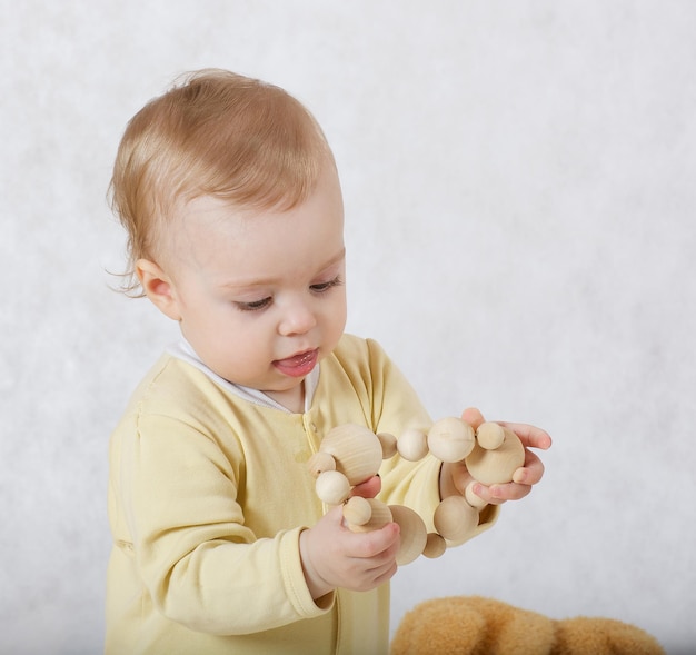 Een babymeisje van acht maanden gekleed in een gele pyjama speelt in haar kamer