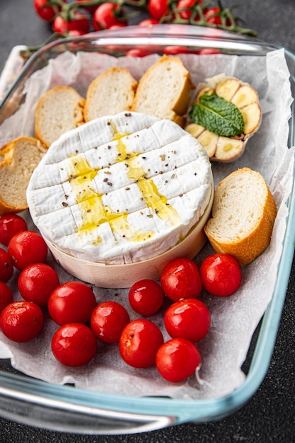 Een bakje kaas en brood met daarop een plakje tomaat.