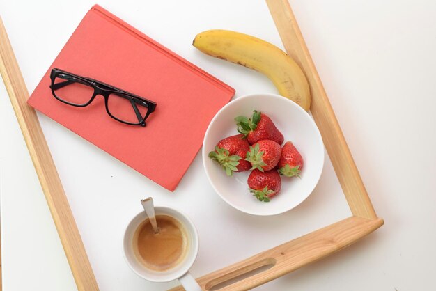 Een bakje met aardbeien een banaan en een banaan erop