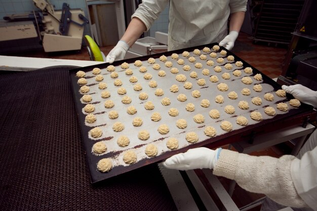 Een bakje met kant-en-klare koekjes wordt van de lopende band in de bakkerij gehaald.