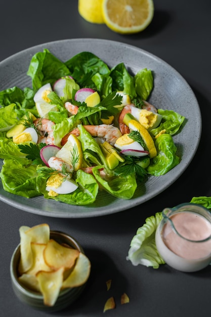 Een bakje salade met een glaasje fruit en een flesje perziksap