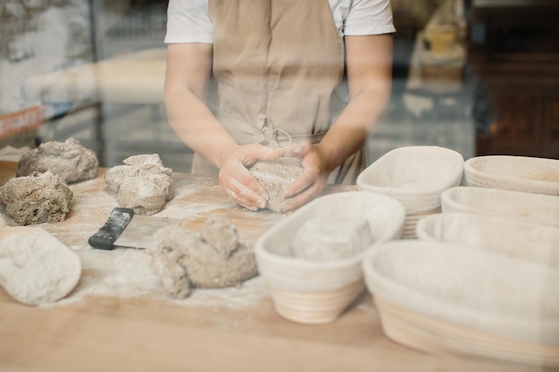 Foto een bakkersvrouw kneedt het deeg en stopt het in een houten vorm bakkerijconcept