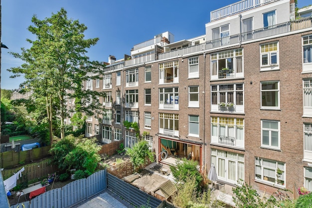Een bakstenen appartementengebouw met veel ramen en een achtertuin