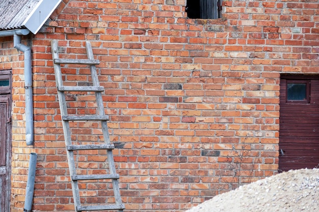 Foto een bakstenen muur met een ladder er tegen aan leunend.