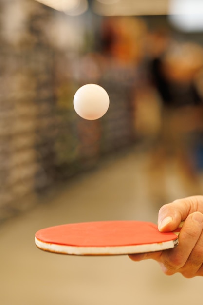 Foto een bal tijdens de vlucht over een tafeltennisracket in de hand van de speler