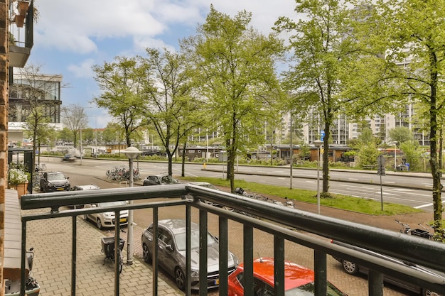 Een balkon met aan de zijkant geparkeerde auto's en bomen langs de straat voor het flatgebouw Amsterdam Nederland