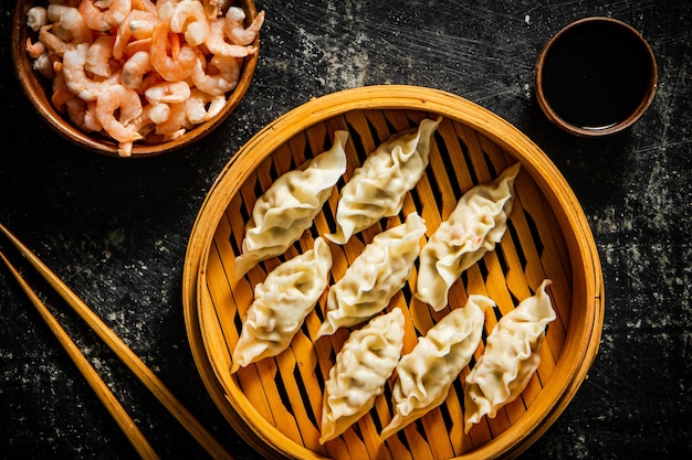 Een bamboe stoommandje met dumplings en garnalen erop.